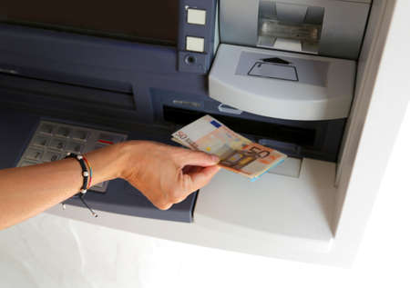 hand of young women while withdrawing banknotes 50 euros from an ATMの写真素材