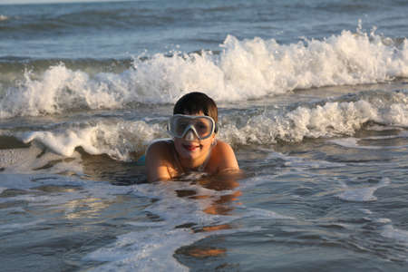 happy child plays diving in the sea wearing a diving maskの写真素材