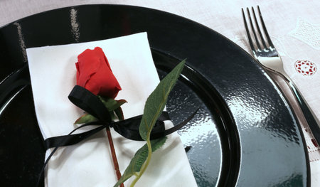 restaurant with elegantly prepared table with a red rose on the black plateの写真素材