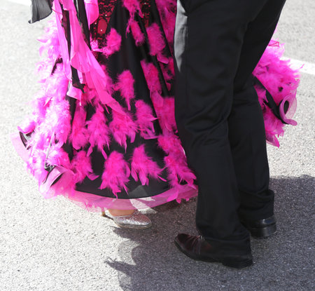 legs of a woman with long fuchsia dress while dancing with a man on the street