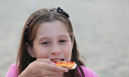 pretty caucasian little girl eats a slice of pizzaの写真素材