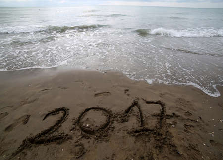 year 2017 on the sand of the sea waiting to be canceled by the wave of the seaの写真素材