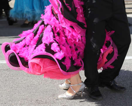 legs of a woman with long fuchsia dress while dancing with a man on the roadの写真素材