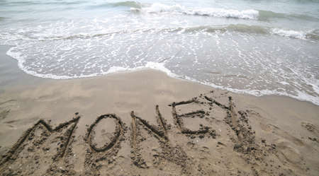 text MONEY written on the sand and wave that is erasing the word symbol of the financial crisis and the loss of moneyの写真素材