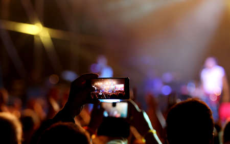 fans who take photos and record videos with modern smartphones during the live concert of a rock bandの写真素材