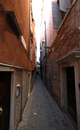 very narrow street called CALLE in Italian Language  between tall houses in Venice Italyの写真素材