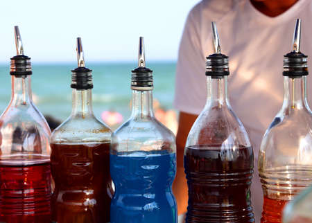 many bottles with sweetened syrup to prepare drinks on the beach by the sea during the summer seasonの写真素材