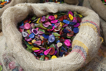 big jute bag full of buttons made with colored palm seeds dried naturally