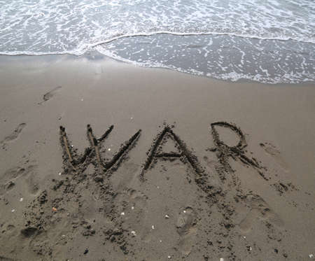 big WAR text and the wave of the sea that wants to erase it on the beachの写真素材