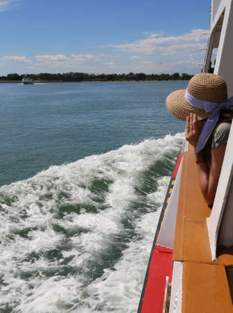 young woman tourist holds the hat because he does not fly away while visiting venice in italyの写真素材