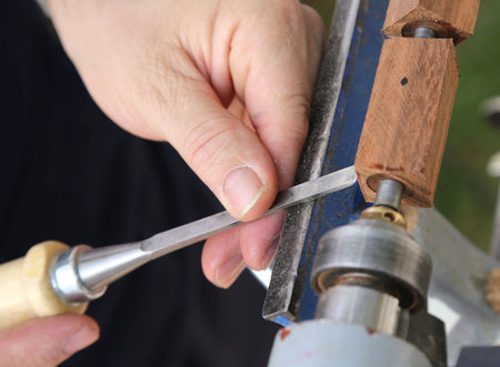 hand of the carpenter while using the lathe and the chisel