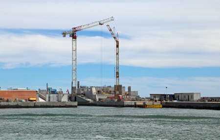 cranes and wide construction site in the sea for building a damの写真素材