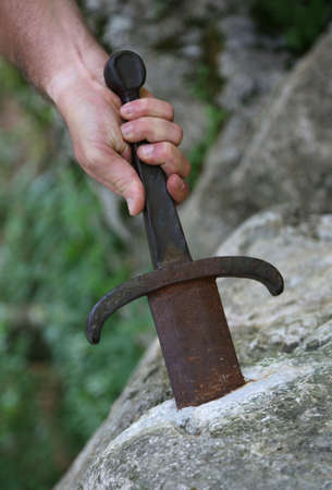 mighty hand trying to draw the sword into the rockの写真素材