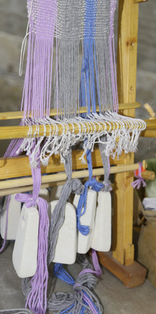 ancient wooden frame to weave the threads and create a fabric, The stones are used as a counterweightの写真素材