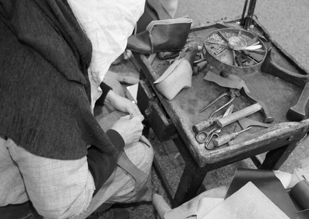 ancient workshop with expert shoemaker during the repair of shoes with black and white effect