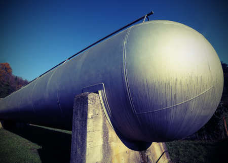 big cylindrical container for the storage of natural gas in an industrial refinery  with vintage style effectの写真素材