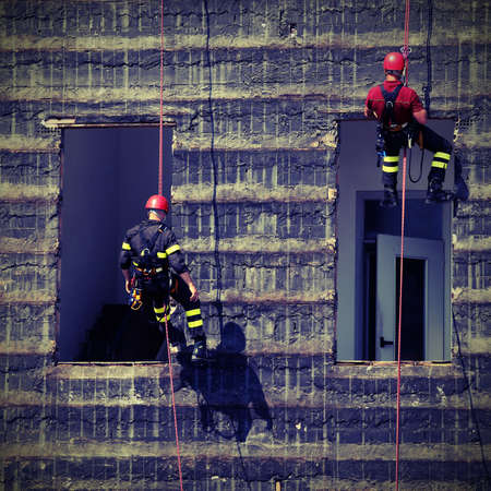 bold and daring climbers of firefighters climbing a wall of a houseの写真素材