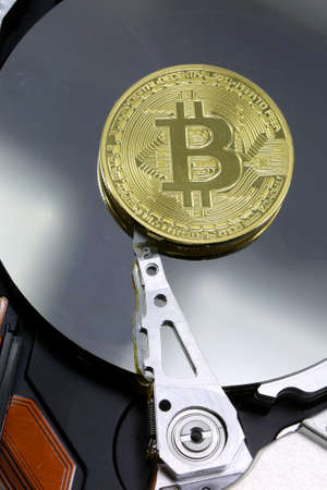golden coin of BITCOIN on a modern computer hard driveの写真素材