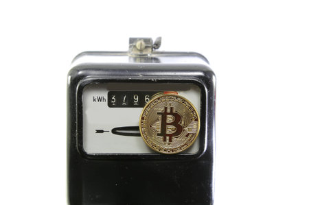 big golden BitCoin coin over an analog electric power meter