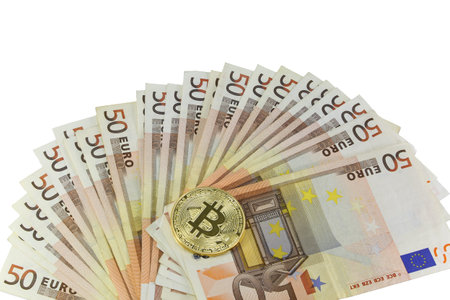 Many 50 euro banknotes and the golden BitCoin coin on white backjgroundの写真素材