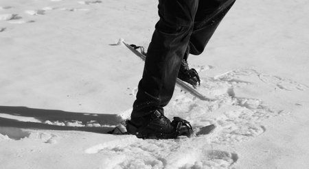 man walks with snowshoes in mountains with black and white effect