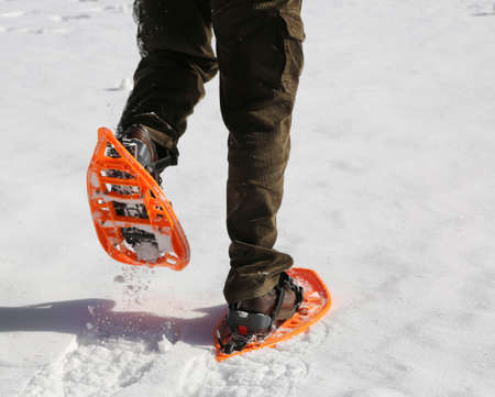 Man with corduroy trousers with snowshoes on white snowの写真素材