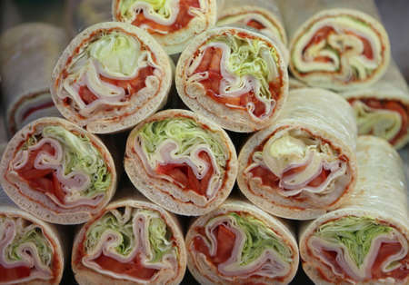 tasty rolled sandwiches with ham and cheese salad for a good snack for sale in the deli shopの写真素材