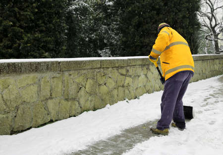 garbage man shovels the snow from the sidewalk after snowfallの写真素材