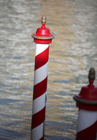Red and white pole to moor boats in Venice in Italyの写真素材