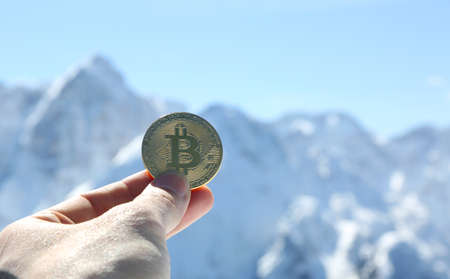 bitcoin coin with hand and a manager and mountains in backgroundの写真素材
