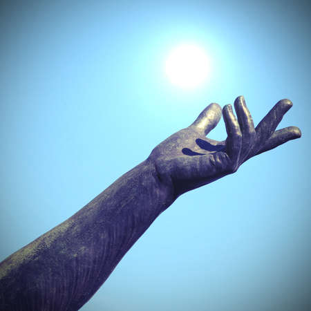 hand of statue trying to catch the white sun in the blue skyの写真素材