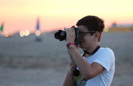 young boy photographer at a beach the sunset on the sea in the summer
