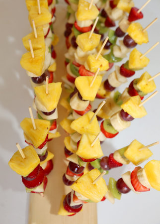 skewers with many pieces of fruit pineapple strawberries kiwi bananaの写真素材