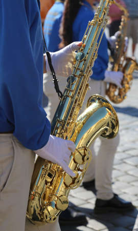 musician with a blue jacket and white gloves playing a saxophone during a paradeの写真素材