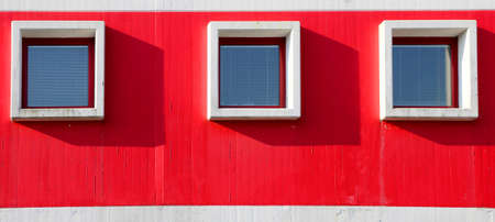 three square windows in the building with red wallの写真素材