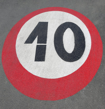 large black and red white road sign painted on the asphalt indicating the maximum speed