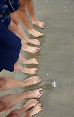 family of five barefoot people on the sand in line on the sandy beach in summer with copyspace on...