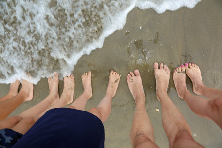family of five barefoot people on the sand by the sea in summer