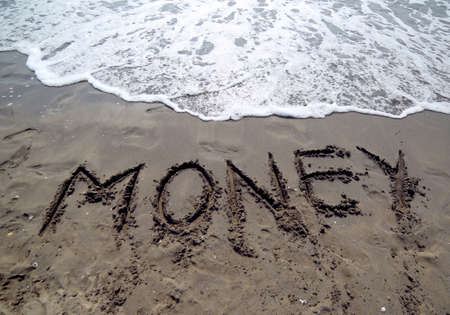 great text MONEY that is canceled by the sea wave on the sandy beachの写真素材