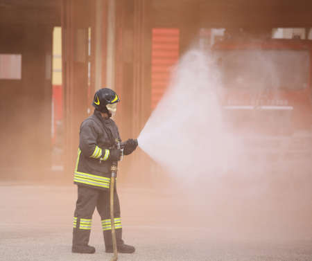 Italia, Italy - May 10, 2018: italian fireman with uniform and helmet uses the hydrant at fire stationのeditorial素材