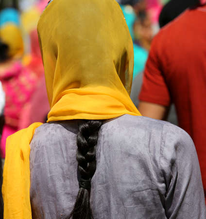 Sikh woman wears a veil on her bright yellow colored hairの写真素材