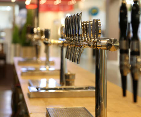 many draft beer taps on the counter of a pubの写真素材