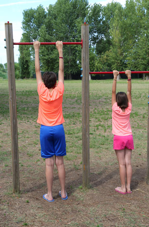 two children one boy and a little girl do gym exercises at the outdoor bar