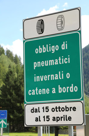 italian traffic sign on highway with text that means obligation of winter tires or snow chains on board from October 15th to April 15thの写真素材