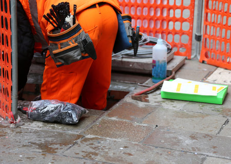 worker with orange overalls during fiber optic repair in the town squareの写真素材