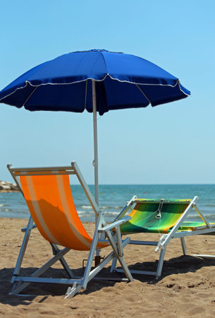 blue beach umbrella and two chairs on the beach of a tourist village