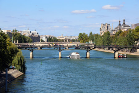 white boat crosses the Seine in Paris passing under a bridge