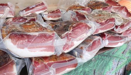 many vacuum packs of speck from South Tyrol for sale in a delicatessen