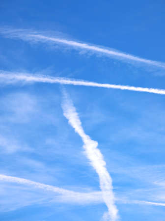 blue sky and white contrails left by airliners or are chemtrails according to the conspiracy theoryの写真素材