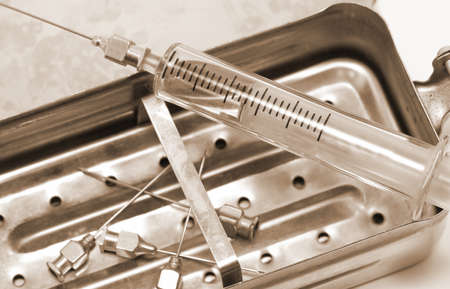 niddles and syringe in glass material with vintage old toned sepia effectの写真素材